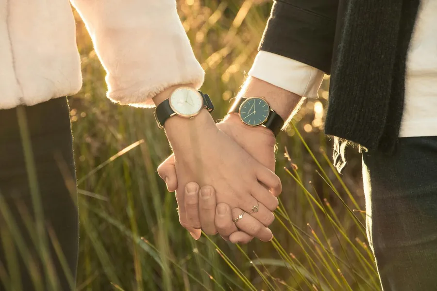 One hand passing a YELM watch to another.