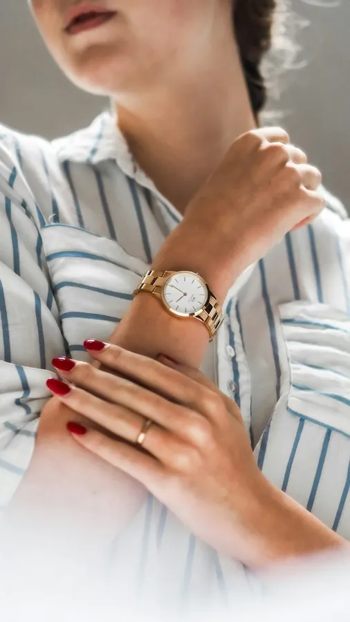 A gold-toned YELM watch worn on a crossed wrist.